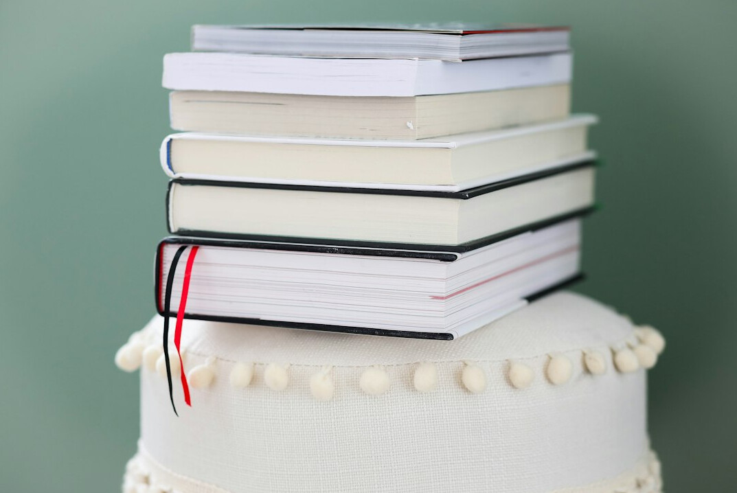Stack of books on a desk beside a laptop